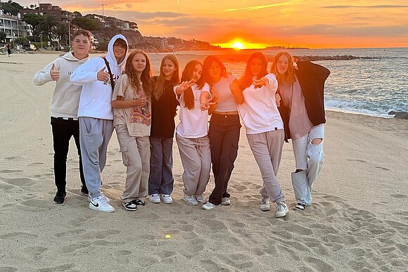junge Menschen vor Sonnenuntergang am Strand