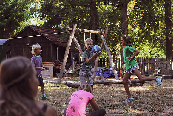 Kinder spielen Ball im Freien mit Spielgeräten
