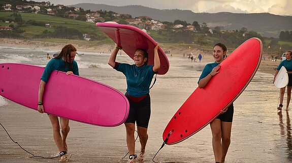 Drei Mädchen am Strand mit Surfbrettern
