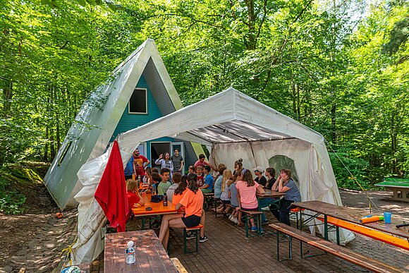 ein Pavillion vor eime Häuschen im Wald