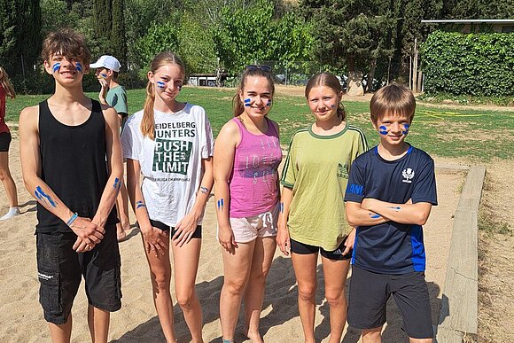 junge Menschen mit Gesichtsbemalung auf Beachvolleyballfeld