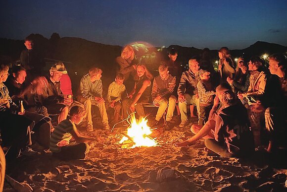 Lagerfeuer mit vielen Menschen vor Sternenhimmel