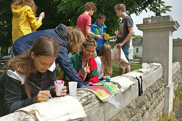 Schülergruppe malt im Freien