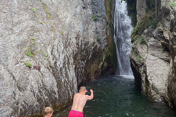 junge Menschen vor Wasserfall hüpfen ins Wasser