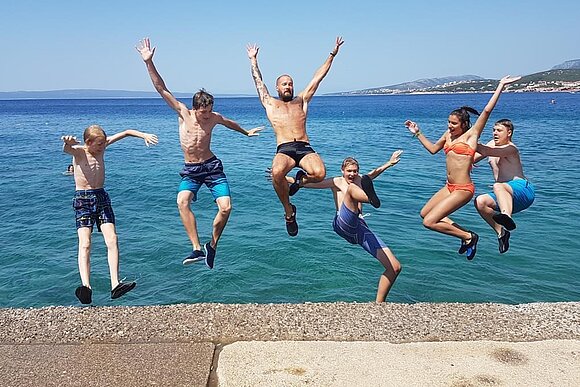 Jugendliche springen ins Meer vom Steg 