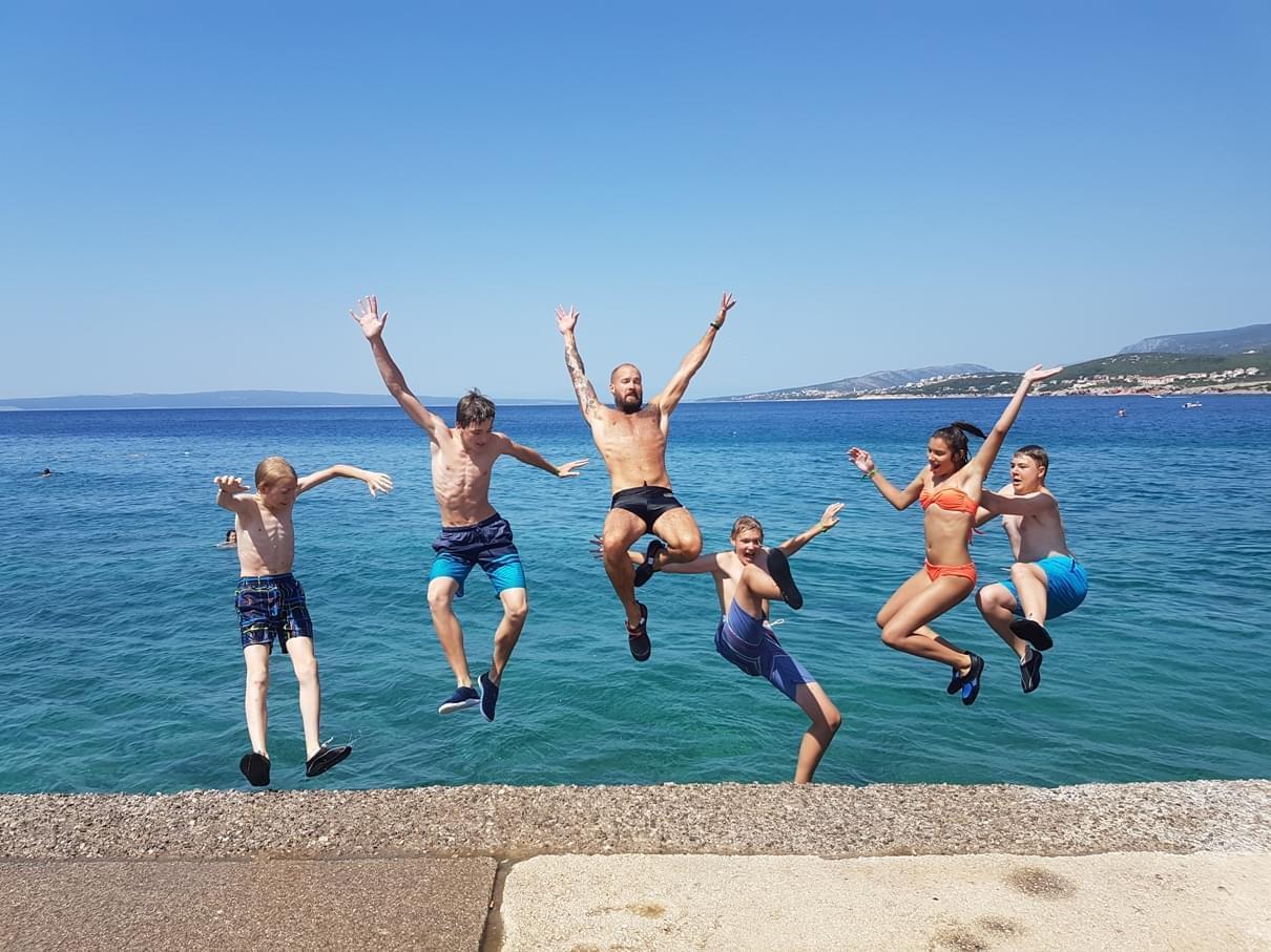 Jugendliche springen ins Meer vom Steg 
